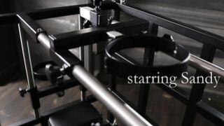 Kinky blonde Sandy E fingers her beaver in a BDSM cage