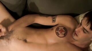 Deviant young man with tattoos strokes his big unshaved prick